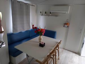 Biały stół z wazonem kwiatów na niebieskiej kanapie w obiekcie Mobilhome 6 pers avec Clim w mieście Saint-Georges-de-Didonne