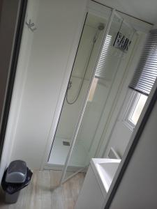 La salle de bains est pourvue d'une douche, d'un lavabo et d'un miroir. dans l'établissement Mobilhome 6 pers avec Clim, à Saint-Georges-de-Didonne