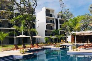 einen Pool in einem Hotel mit Stühlen und Sonnenschirmen in der Unterkunft COZY UNIT at Bambu Residencial & AMAZING POOL in Puerto Vallarta