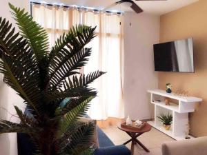 ein Wohnzimmer mit einer Palme vor einem Fenster in der Unterkunft COZY UNIT at Bambu Residencial & AMAZING POOL in Puerto Vallarta