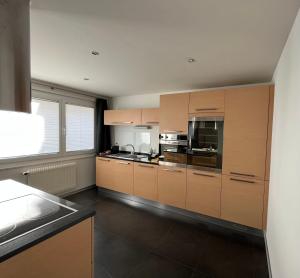 a large kitchen with wooden cabinets and a window at Appartement Tourbillon centre-ville in Sion