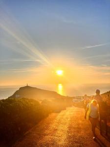 a group of people walking down a road at sunset at Syds Corner bell tent in St. Just