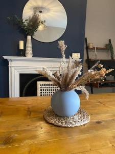 a blue vase on a wooden table with a plant in it at Homely 2-bed Terrace with Log Burner in Lincolnshire