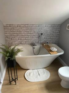 a white bath tub in a bathroom with a brick wall at Homely 2-bed Terrace with Log Burner in Lincolnshire
