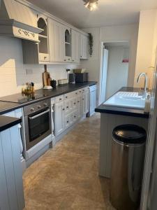 a kitchen with white cabinets and a trash can at Homely 2-bed Terrace with Log Burner in Lincolnshire