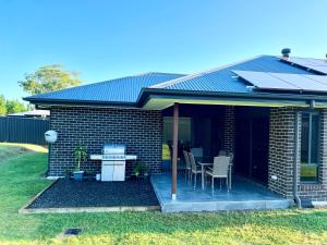 a brick house with a table and chairs on a porch at Plantation Retreat 4 Bedroom Modern Home in Landsborough