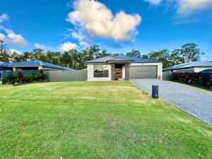 a house with a garage and a grass yard at Plantation Retreat 4 Bedroom Modern Home in Landsborough