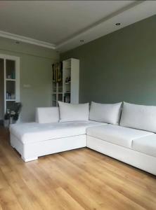 ein weißes Sofa im Wohnzimmer mit Holzböden in der Unterkunft Full house in Fenerbahce in Istanbul