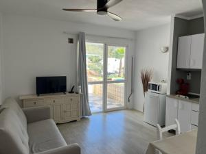 a living room with a couch and a tv and a kitchen at Apartamentos Cana Sofía in Cala Llonga