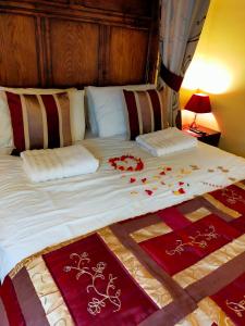 a bed with red and white blankets and pillows at Meadow Farm Cottage in Norwich
