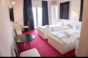 ブゴイノにあるApartmani i sobe Centar Bugojnoのベッド2台とテーブルが備わるホテルルームです。