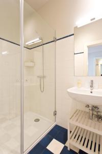 La salle de bains blanche est pourvue d'un lavabo et d'une douche. dans l'établissement BOUTIQUE Rentals- P*O*R*T*O Ribeira, à Porto