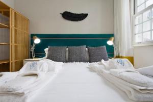 - une chambre dotée d'un grand lit avec des draps et des oreillers blancs dans l'établissement BOUTIQUE Rentals- P*O*R*T*O Ribeira, à Porto