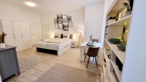 a white bedroom with a bed and a desk at Stadtgarten-Studios - im Zentrum mit Parkplatz in Weingarten