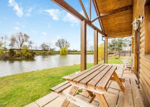 a wooden porch with a picnic table and a lake at Camper Uk Leisure Park in Doddington