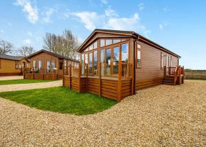a large wooden cabin with windows on the grass at Camper Uk Leisure Park in Doddington