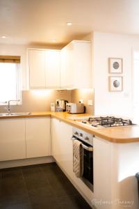 a kitchen with white cabinets and a stove top oven at The Lookout, Modern Home from Home, Sleeps 5, with private parking & outside terrace in St Ives