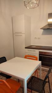a kitchen with a white table and orange chairs at APPARTAMENTO LA SPIAGGETTA in Foligno