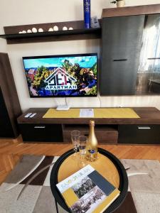 sala de estar con TV y mesa con copas de vino en DEX Apartman en Salgótarján