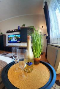 a table with two wine glasses and a bottle on it at DEX Apartman in Salgótarján