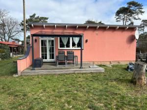 a small pink house with chairs on a deck at Gemütlicher Bungalow am Meer in Pepelow in Pepelow