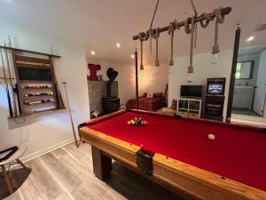 a red pool table in a living room with at Bungalow sur le lac in Chertsey