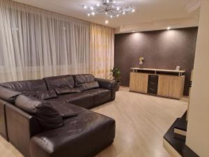 a living room with a leather couch and a tv at Good J&I apartment in Balvi