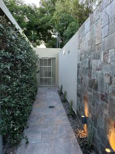 einen Gehweg, der zu einem Gebäude mit einer Steinmauer führt in der Unterkunft Orfila Apart 1 in Mendoza