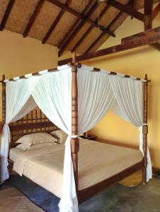 a bedroom with a canopy bed with white curtains at Waiara Village Guesthouse in Maumere