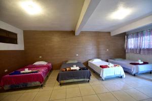 a room with three beds and two tables in it at CASA EL ROBLE in San Juan La Laguna
