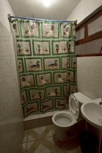 y baño con aseo y cortina de ducha. en CASA EL ROBLE en San Juan La Laguna