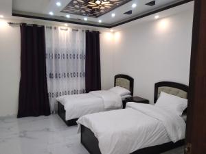 2 Betten in einem Zimmer mit weißer Bettwäsche in der Unterkunft Petra Inn House in Wadi Musa