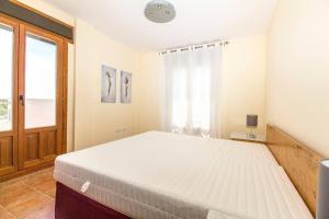 1 dormitorio con 1 cama blanca grande y ventana en Dream Penthouse next to the beaches of the Algarve, en Ayamonte