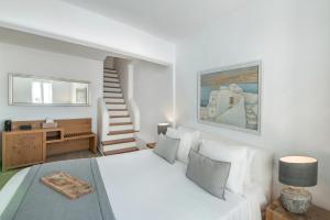 a white bedroom with a bed and a staircase at Aqua Luxury Suites by NOMÉE Hospitality Group in Imerovigli +55 photos