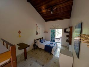 a bedroom with a bed and a table in a room at Pousada Nova Ascalom in Ubatuba