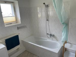 a white bathroom with a tub and a shower at Monteur Ferienwohnung OT Kleinwaltersdorf mit Außensitzecke und Grill in Freiberg