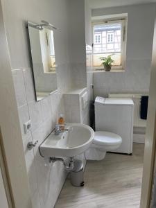 a white bathroom with a sink and a toilet at Monteur Ferienwohnung OT Kleinwaltersdorf mit Außensitzecke und Grill in Freiberg