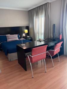 Schlafzimmer mit einem Schreibtisch mit 2 Stühlen und einem Bett in der Unterkunft HOTEL PERDIZES - FLAT Executivo - 1403 in São Paulo