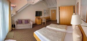 pokój hotelowy z łóżkiem i kanapą w obiekcie Sporthotel Schönblick w mieście Meersburg