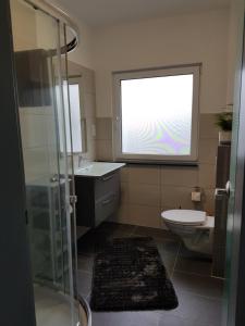 ein Bad mit einem Waschbecken, einem WC und einem Fenster in der Unterkunft FeWo mit Terasse Neuwied & Koblenz in Neuwied