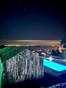 a swimming pool at night with a city in the background at Cabañas Rias Baixas in Pobra do Caramiñal