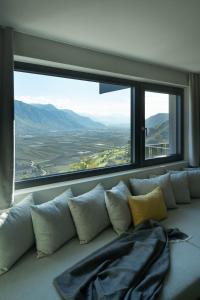 - un canapé avec des oreillers devant une grande fenêtre dans l'établissement My Spring - Panoramic Suites, à Lana