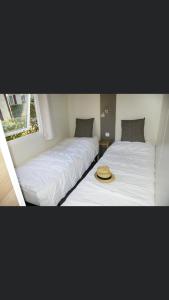 two beds with white sheets and a hat on them at Camping Siblu domaine de Dugny in Onzain