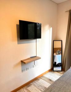1 dormitorio con TV de pantalla plana en la pared en Patagonia Host, JAMA en Villa La Angostura