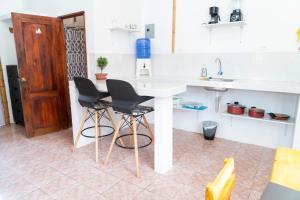 a kitchen with a white counter and two chairs at Surfside BEACH FRONT CABANAS in Montañita