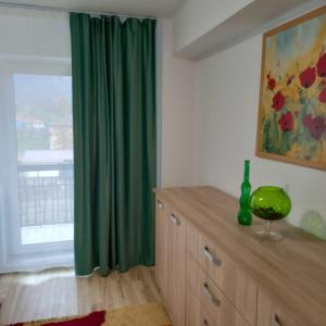 a room with a green curtain and a dresser with a window at Apartament Hanna - Straja in Uricani