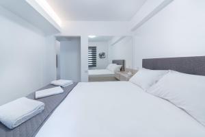 ein weißes Schlafzimmer mit einem großen Bett und einem Badezimmer in der Unterkunft Lydia's Apartment in Iraklio
