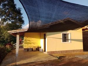 a yellow house with a blue covering over it at Sítio Ramos casa amarela in Cunha