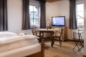 a bedroom with a bed and a desk with a television at Landgasthof Augustiner in Oberstdorf