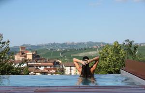 een vrouw in een zwembad die naar een stad kijkt bij Villa Carla Suites in Barolo in Barolo